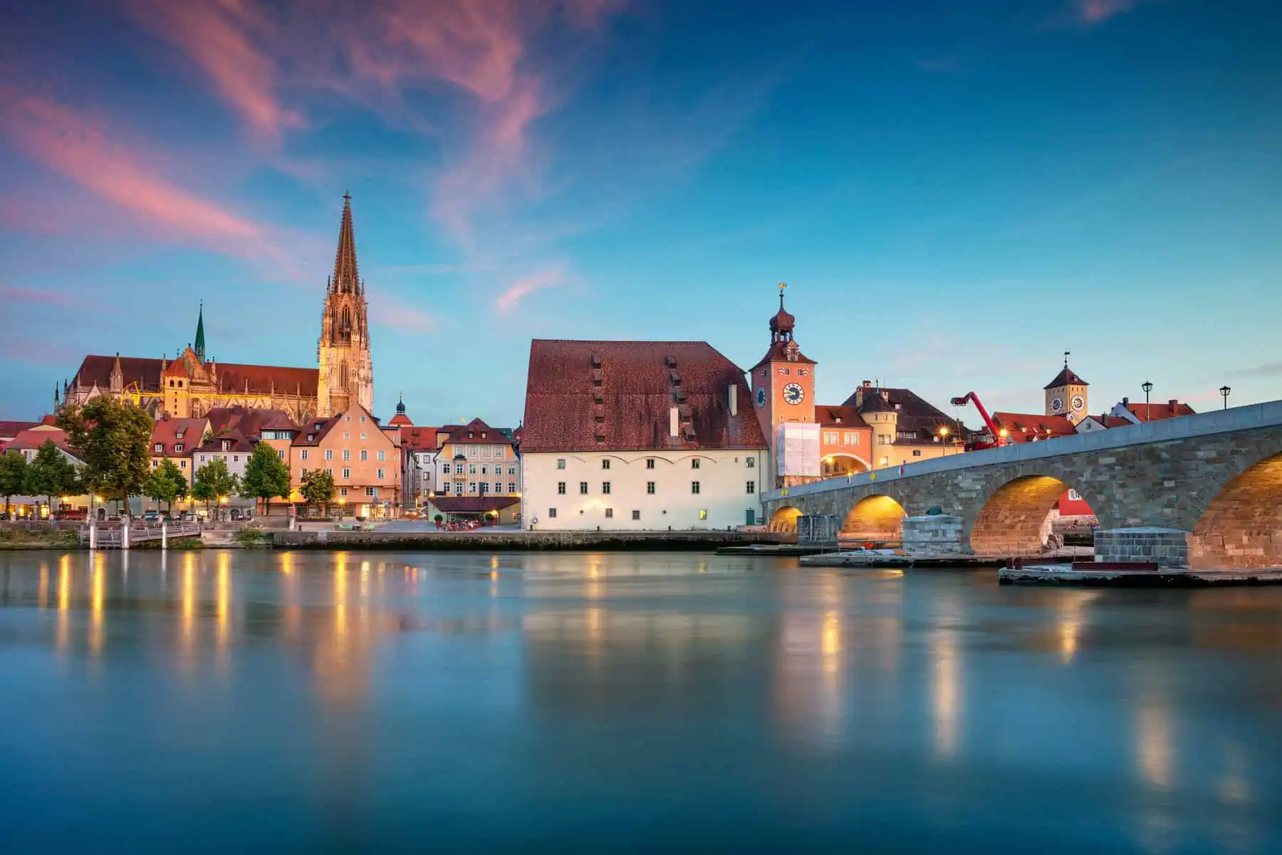 Regensburg in der Abenddämmerung: Blick über die Donau auf die Steinerne Brücke, den Brückturm, das Salzstadel und den Dom